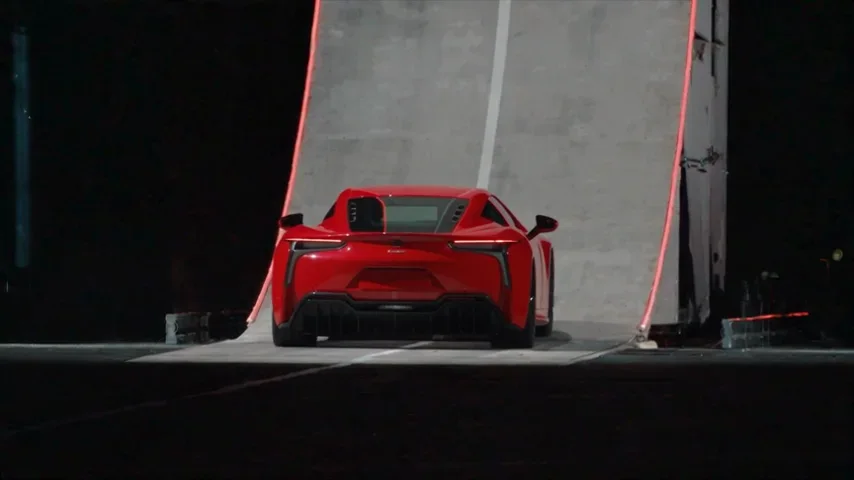 An unbranded red sports coupe facing a towering stunt ramp